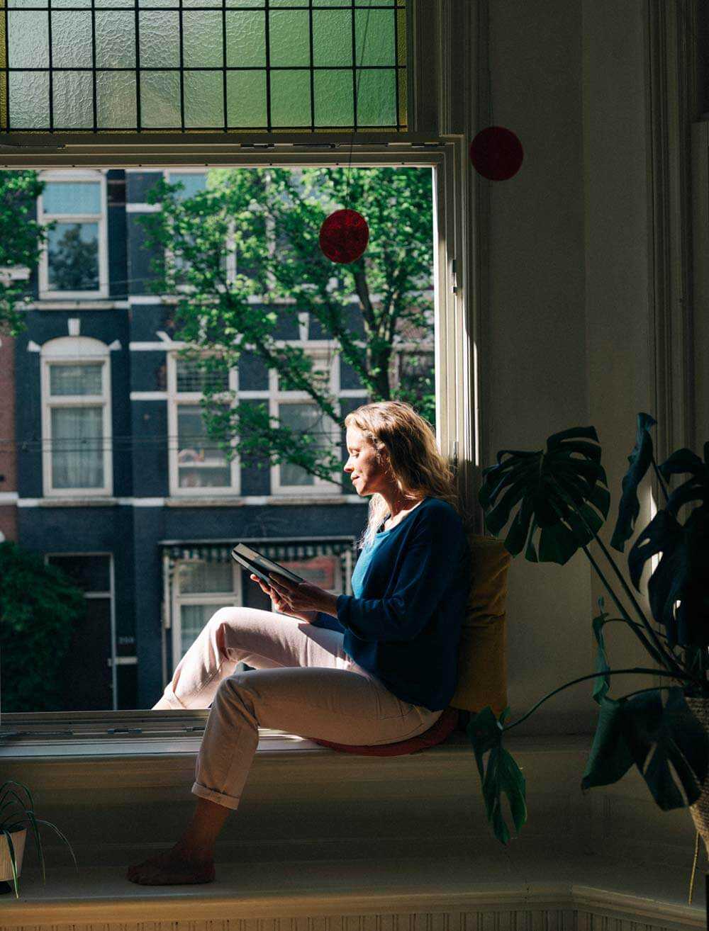 Vrouw aan het lezen bij het raam