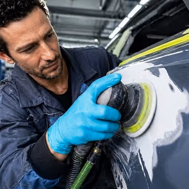 Een man repareert lakschade in een werplaats