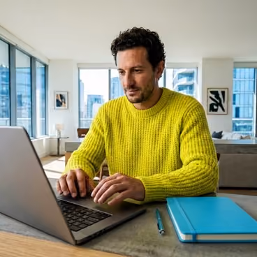 Een man zit achter zijn laptop.