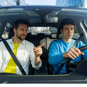 een jongen en een man zitten samen in een auto en de man geeft aanwijzingen