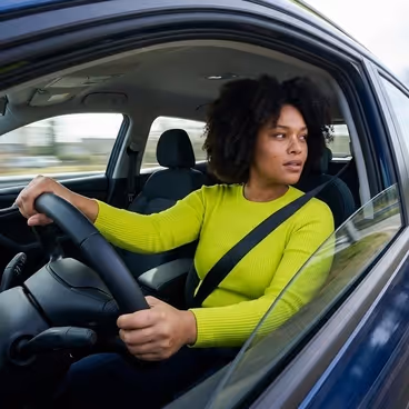 Een vrouw zit achter het stuur van haar auto