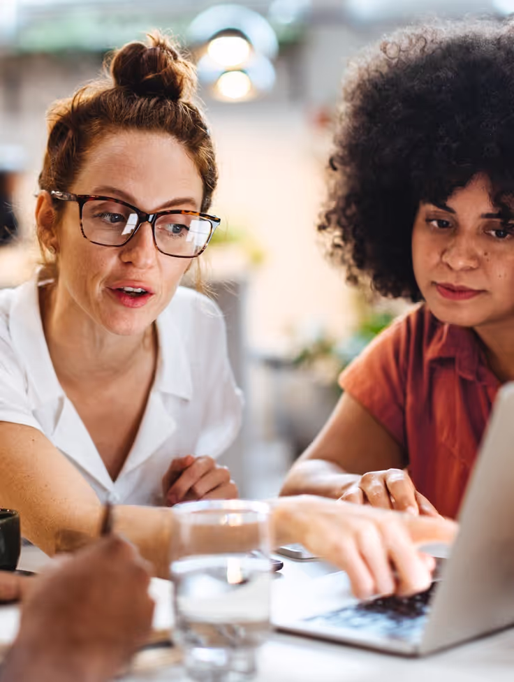 Twee vrouwen discussiëren terwijl ze naar een beeldscherm kijken.