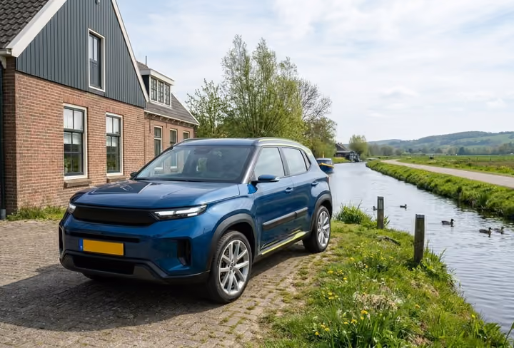 Een blauwe suv staat geparkeerd voor een groot huis in een landelijke omgeving