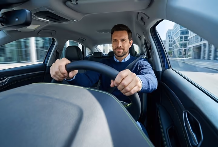 Een man zit achter het stuur van zn auto