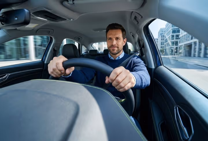 Een man zit achter het stuur in zijn auto