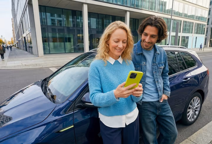 twee mensen staan voor de auto met een telefoon in de hand