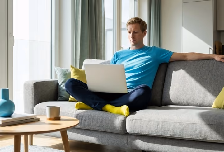 man zit achter zijn laptop op de bank