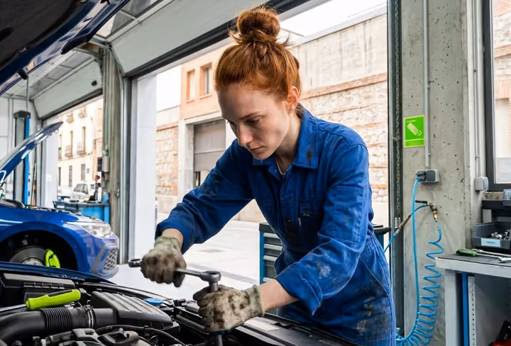 vrouwelijke automonteur werkt aan een auto