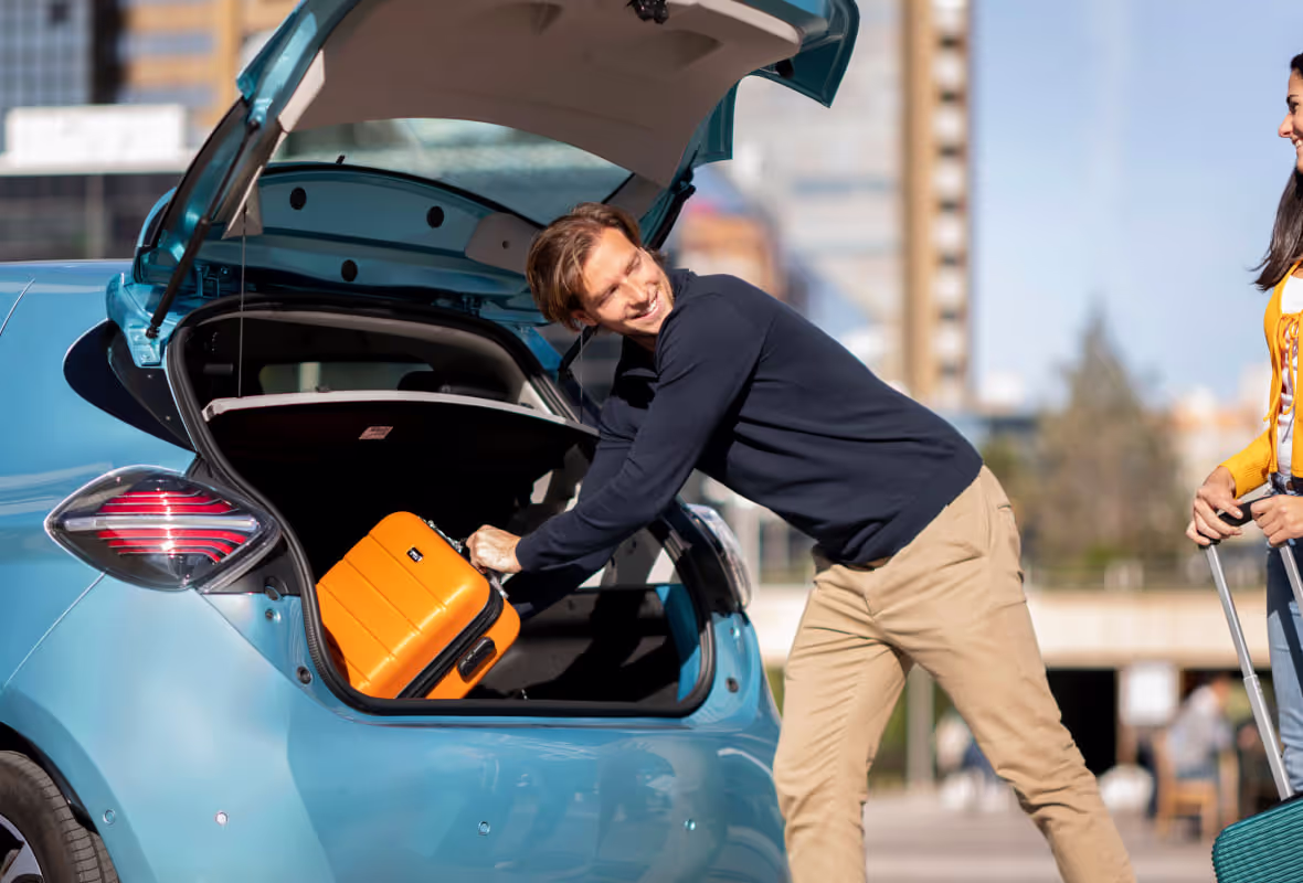 Man stopt koffer in auto