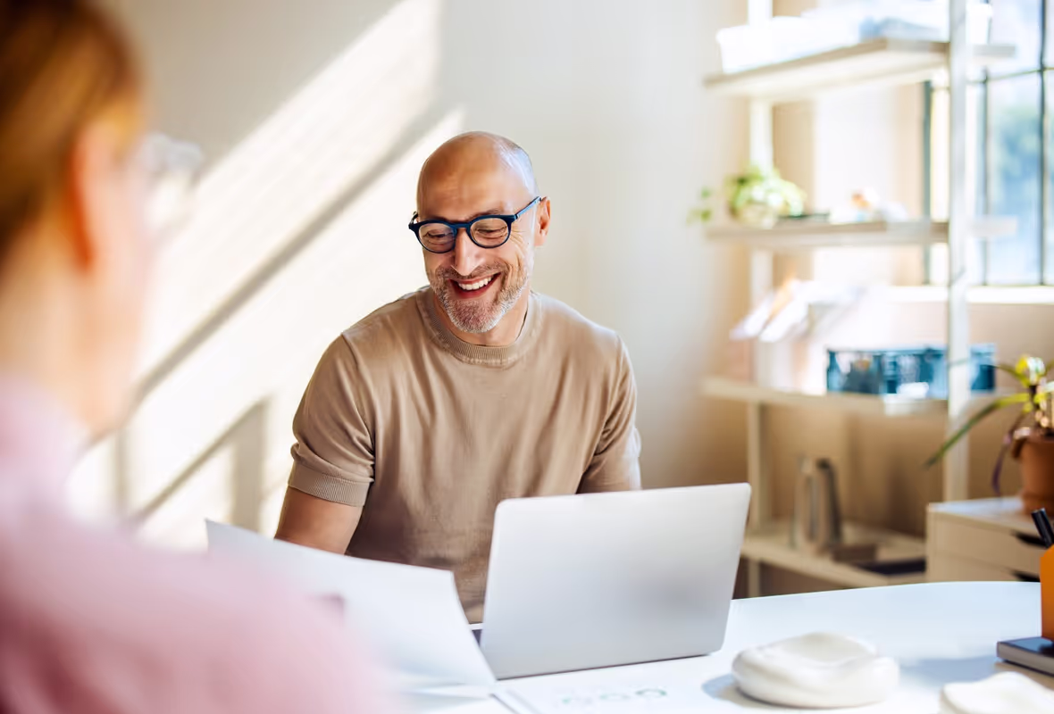 Man zit in zonnige kamer en bekijkt lachend een document