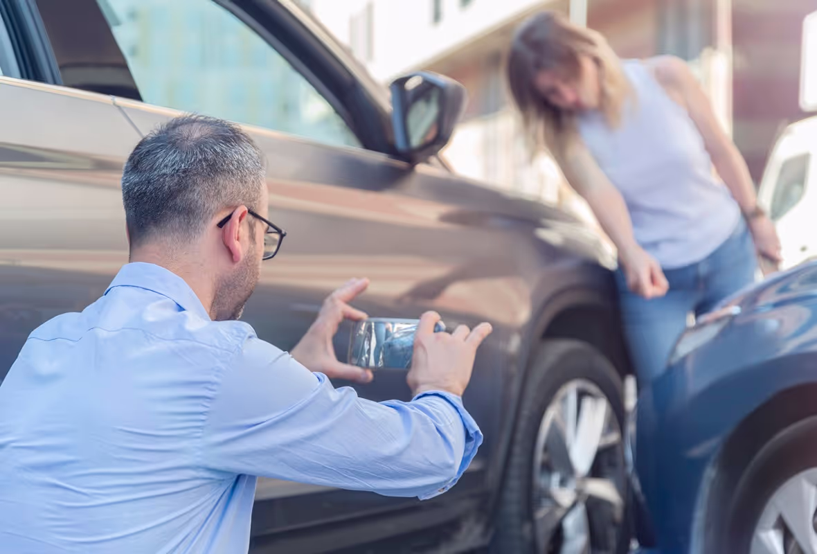 Een man maakt een foto met zijn telefoon van autoschade na een ongeluk