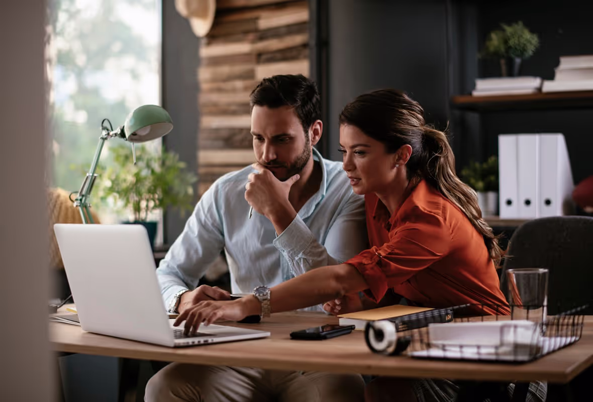 Een man en vrouw zitten achter een computer en bespreken at ze op het scherm zien. 