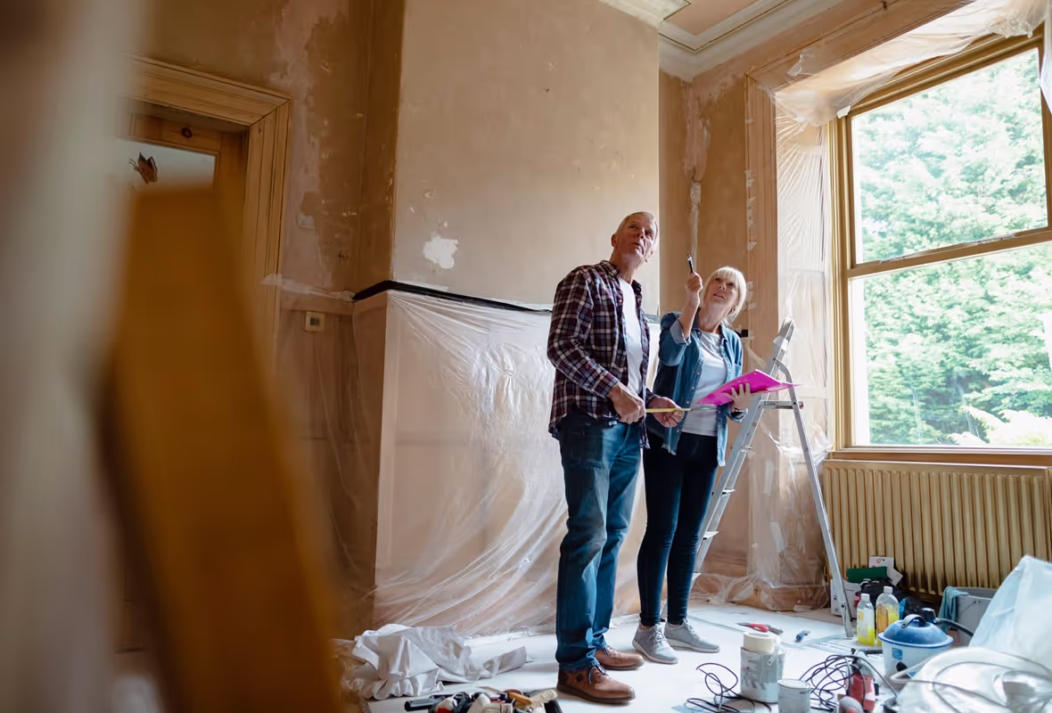 Een ouder stel staat in een kamer waar hard wordt geklust  en kijkt verkennend om zich heen