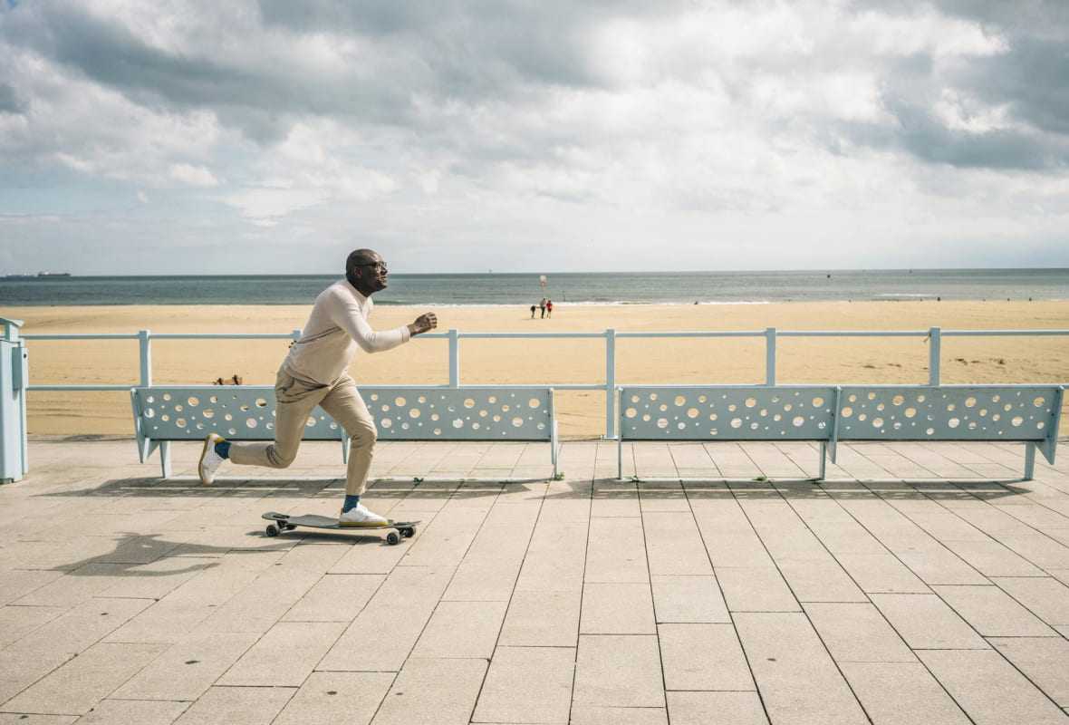 Man op skateboard aan de kust
