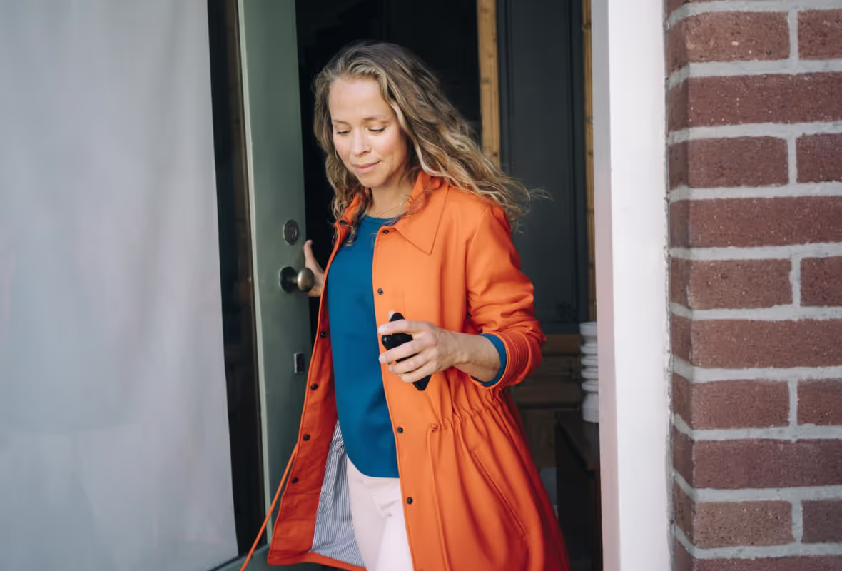 Vrouw komt de deur uit en lacht