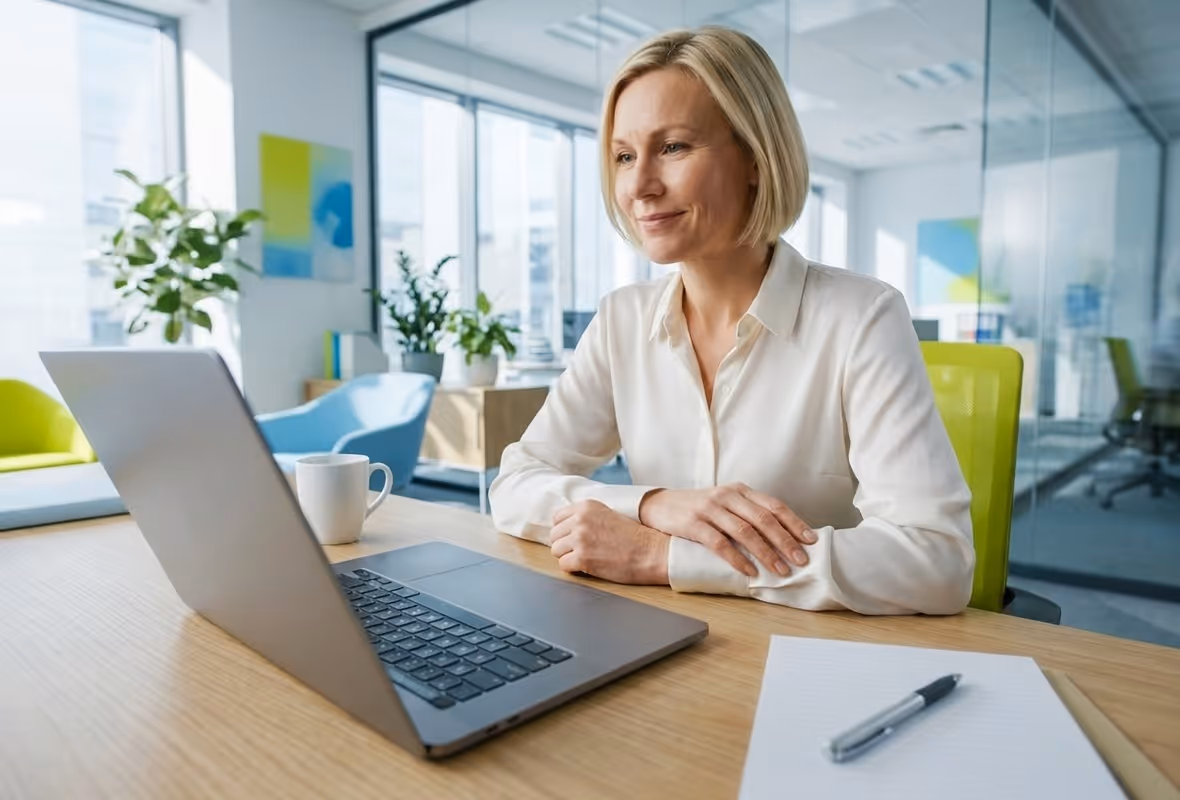 Een vrouw zit achter haar laptop en kijkt naar het scherm