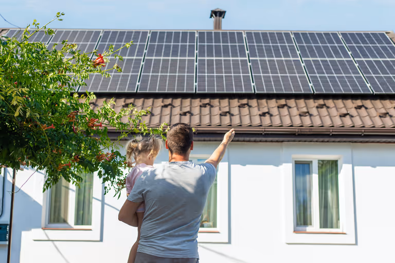 Vader en kind kijkend naar zonnepanelen op het dak
