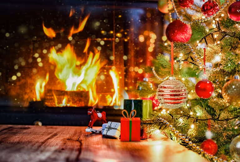 Vuur in haard met versierde kerstboom ernaast