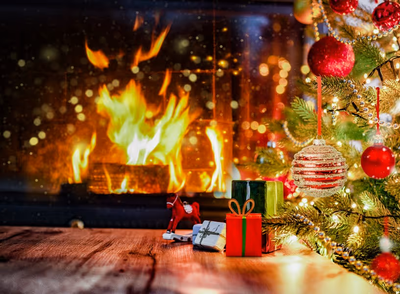 Vuur in haard met versierde kerstboom ernaast