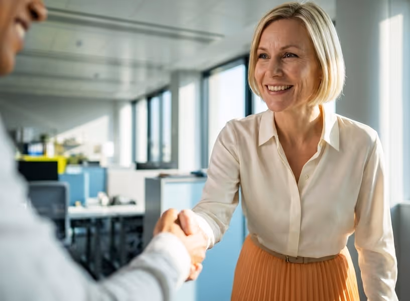 Vrouw schudt lachend de hand van een man tegenover haar
