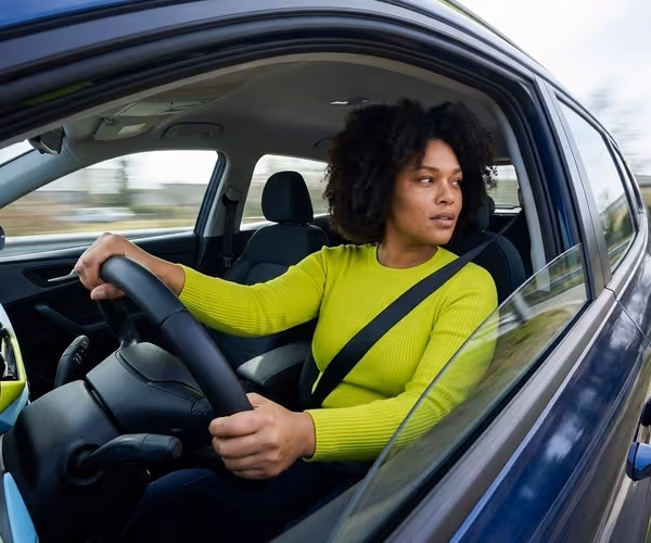 Een vrouw rijdt over de snelweg en kijkt over haar schouder uit het autoraam