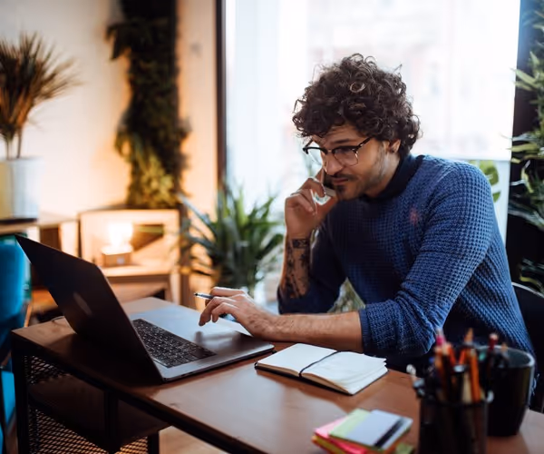 Een man zit achter zijn laptop