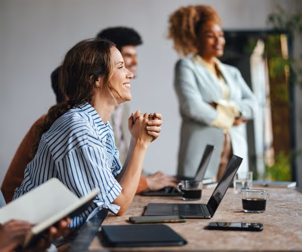 Vrouw zit lachend in een vergaderruimte