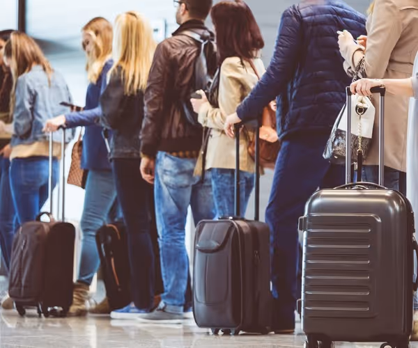 Een groep mensen staat in de rij op het vliegveld met rolkoffers
