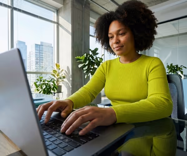 Een vrouw zit achter de laptop in haar woonkamer