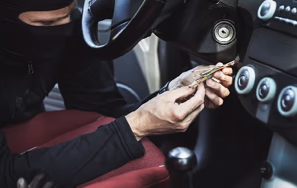 Iemand probeert een auto te stelen door twee draadjes onder het stuur met elkaar te verbinden. 