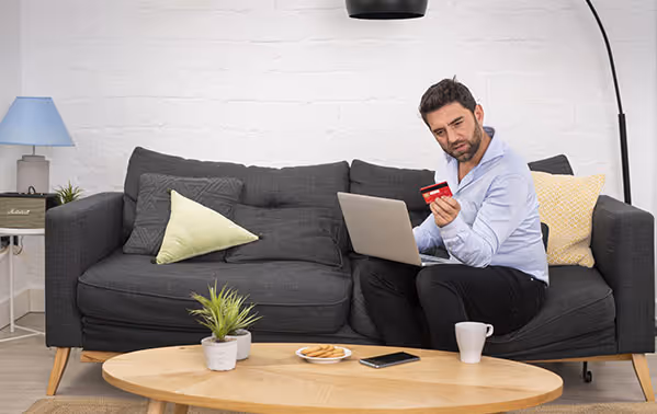 Man op bank met laptop telefoon